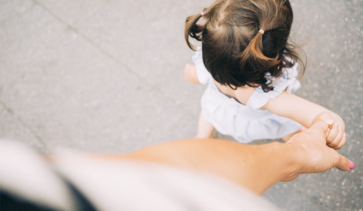 Toddler girl walking holding mother's hand