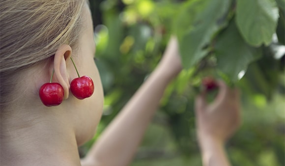 Girl picking fruit and wearing cherries as earrings