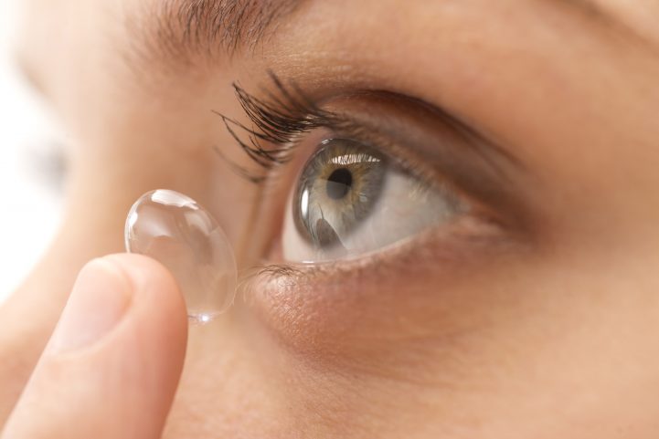 Young woman putting in contact lens, close-up