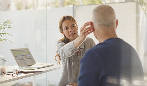 Female doctor helping male patient with hearing aid in doctors office